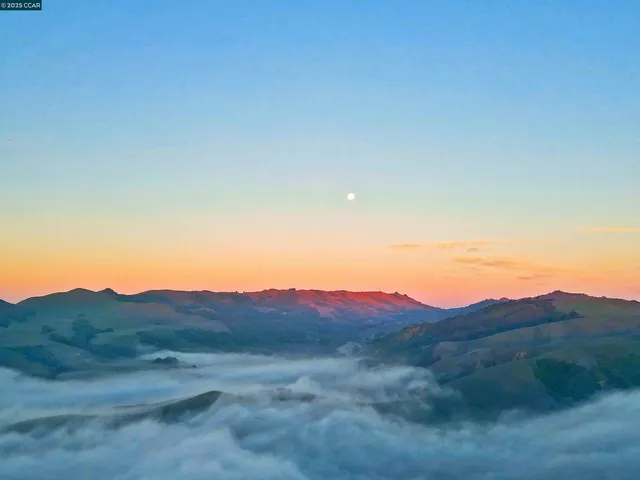 a backyard of a house with table and chairs under an umbrella