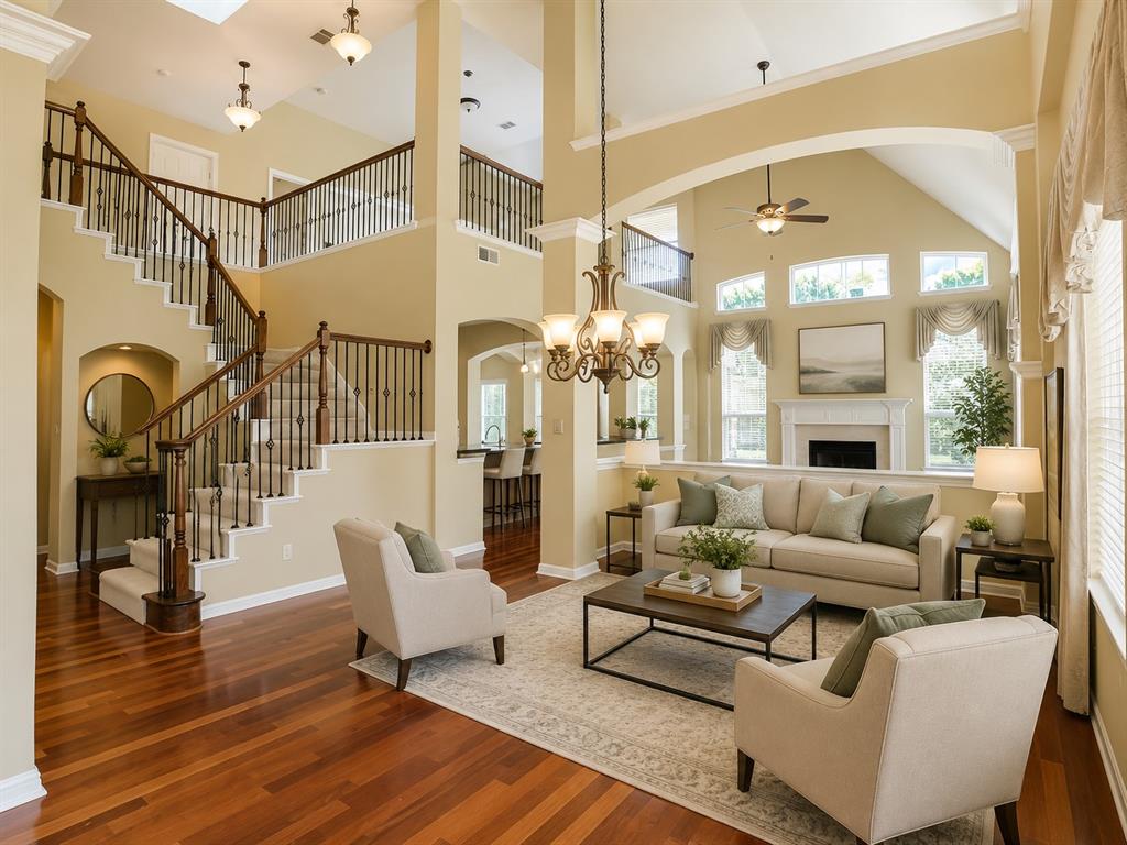 5708 Rickshaw Lane Plano, TX 75094 - Photo 5 of 28 Two-story living area featuring a prominent fireplace with mantel, multiple arched window banks, and a grand staircase with wood railings and wrought iron spindles