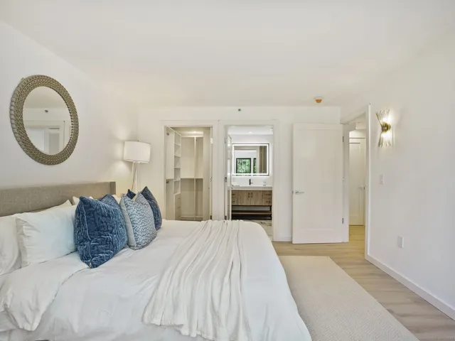 a spacious bedroom with a bed a mirror and a lamp