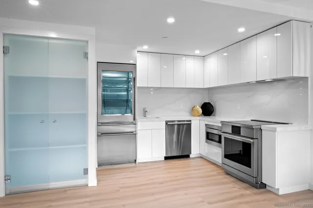a kitchen with granite countertop white cabinets and stainless steel appliances