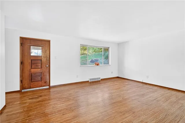 an empty room with wooden floor closet and windows