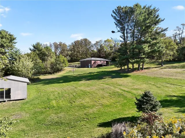 a view of backyard with large trees and a barn in it