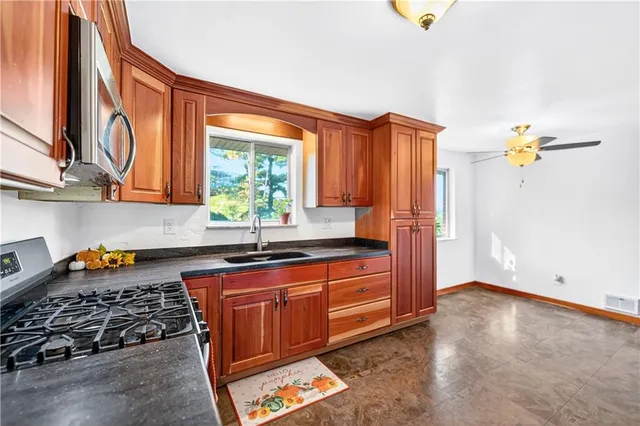 a kitchen with stainless steel appliances granite countertop a stove a sink and a microwave