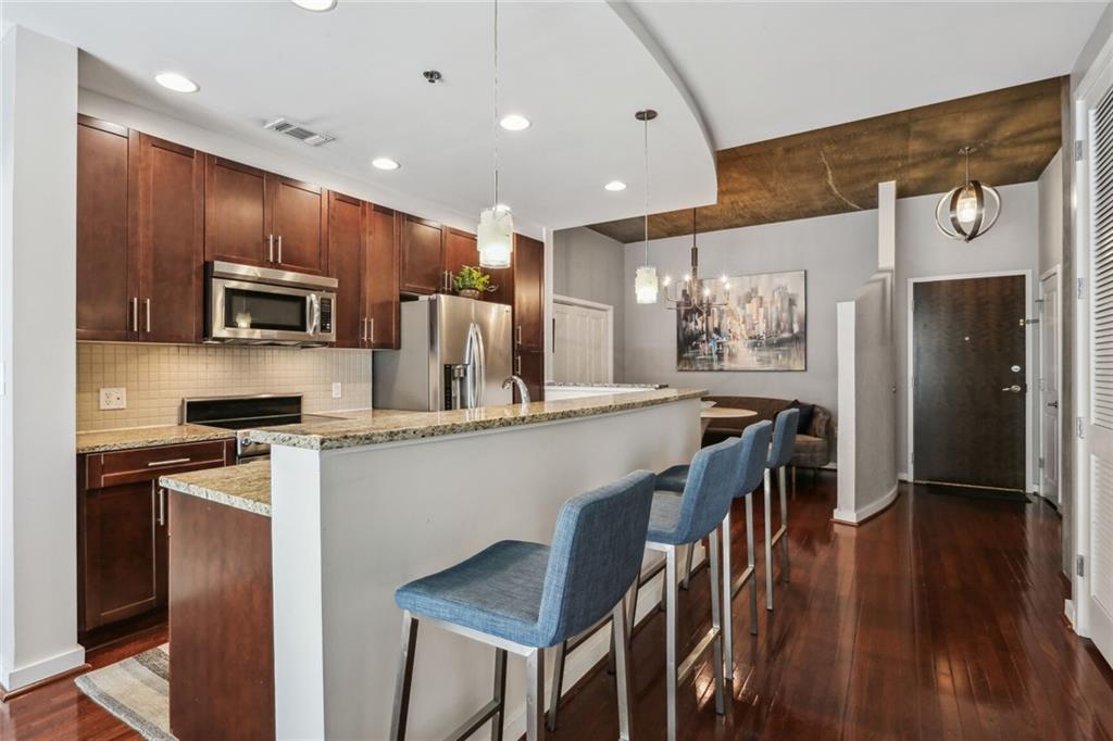 a kitchen with stainless steel appliances granite countertop a refrigerator a stove top oven a sink dishwasher and wooden cabinets with wooden floor