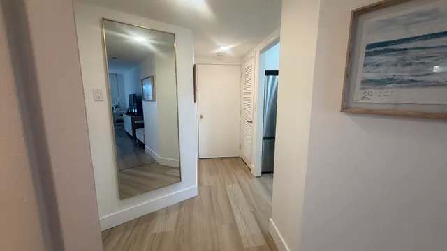 a view of a hallway with wooden floor and a bathroom