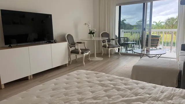 a living room with furniture a flat screen tv and a floor to ceiling window