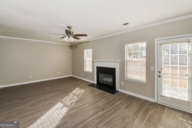 a view of an empty room with wooden floor fireplace and a window