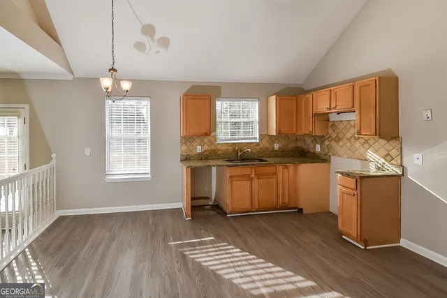 a kitchen with a sink stove cabinets and wooden floor