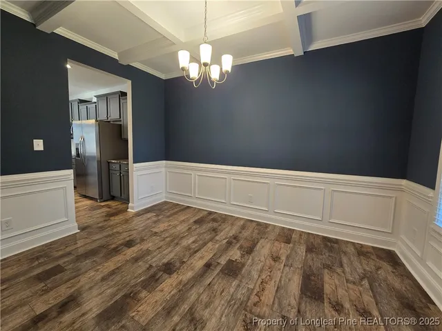 a view of an empty room with wooden floor and staircase