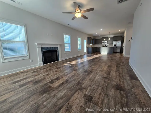 a view of empty room with kitchen and fireplace