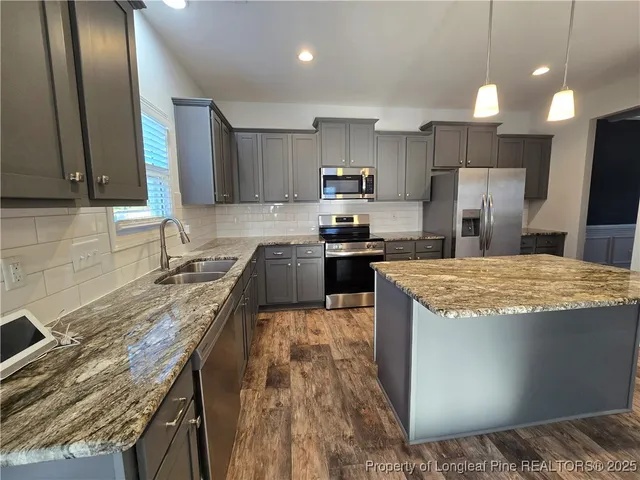 a kitchen with kitchen island granite countertop a sink stove and refrigerator