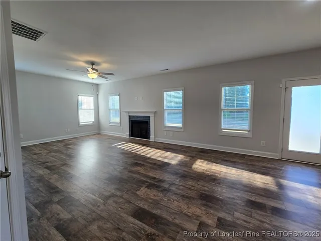 a view of an empty room with window and wooden floor