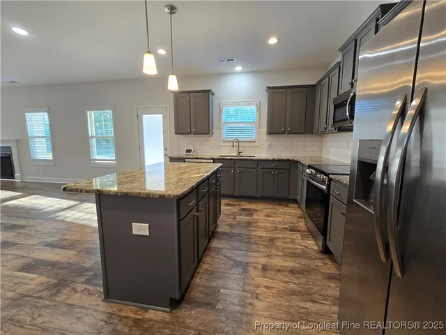 a kitchen with stainless steel appliances granite countertop a sink a counter top space cabinets and wooden floor