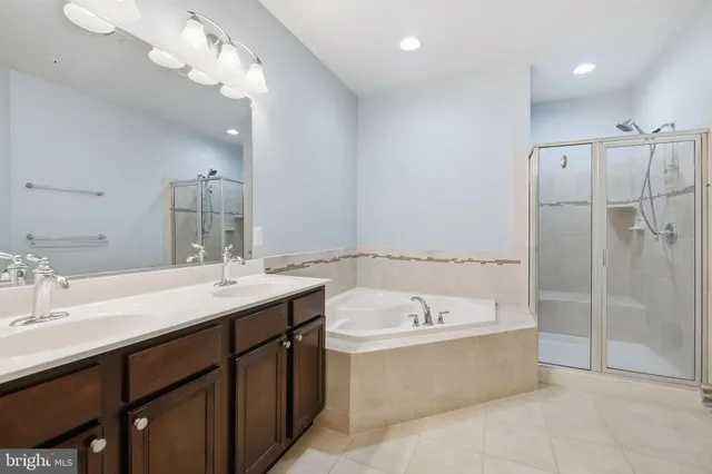 a bathroom with a tub a double vanity sink and mirror