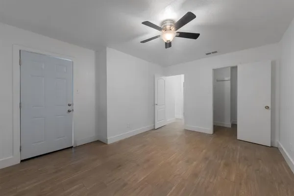 an empty room with chandelier fan and windows