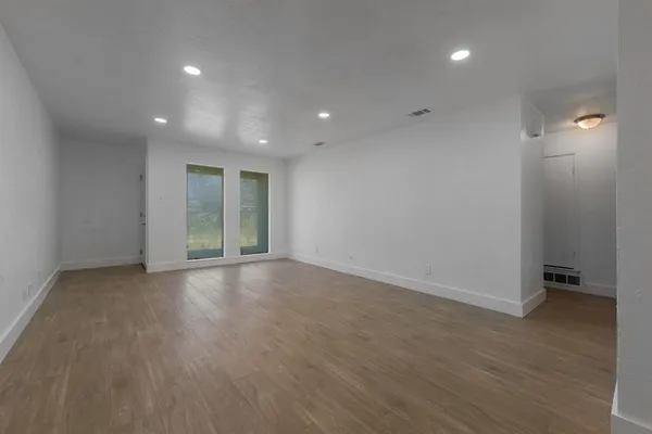 an empty room with wooden floor and windows