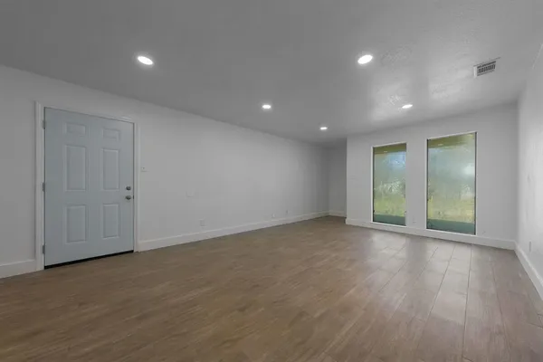 a view of an empty room with wooden floor and a window