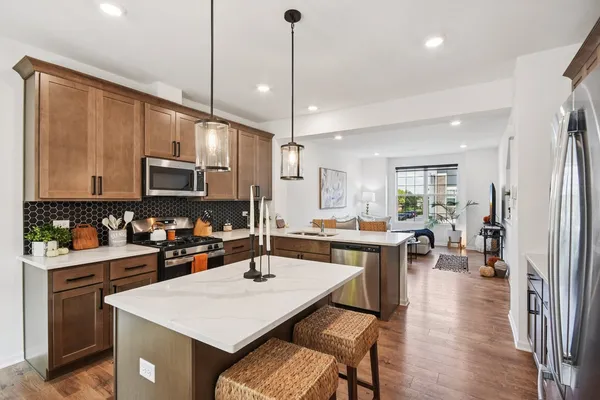 a kitchen with a stove a refrigerator a sink a dining table and chairs with wooden floor