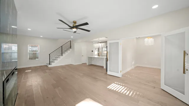 a view of empty room with wooden floor and fan