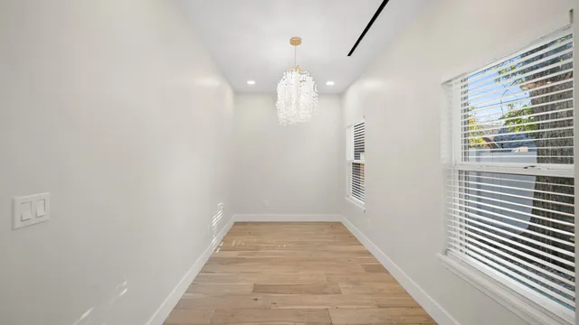a view of a hallway with wooden floor and a bathroom