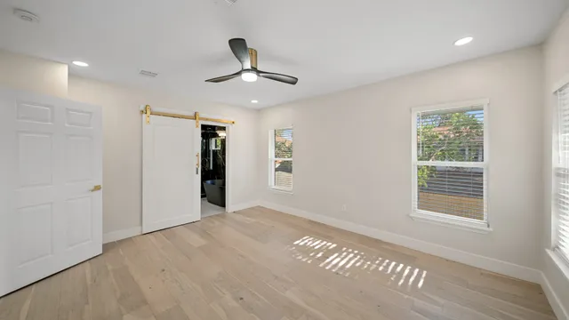 a view of an empty room with a window and wooden floor