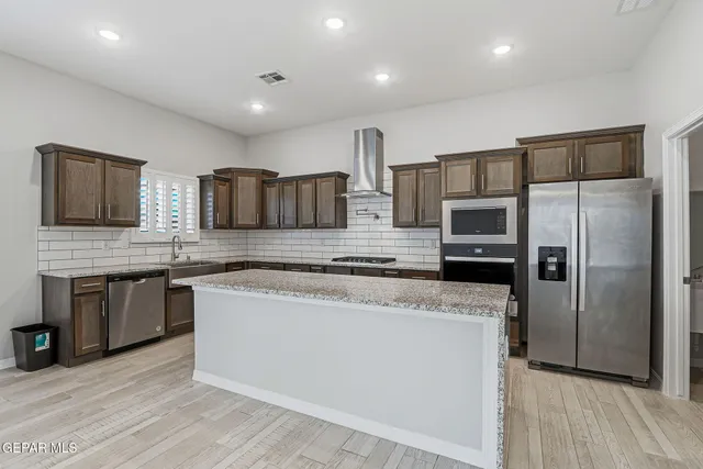 a kitchen with stainless steel appliances granite countertop a refrigerator a stove a sink and a microwave