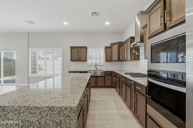 a large kitchen with stainless steel appliances granite countertop a stove a sink and a granite counter tops