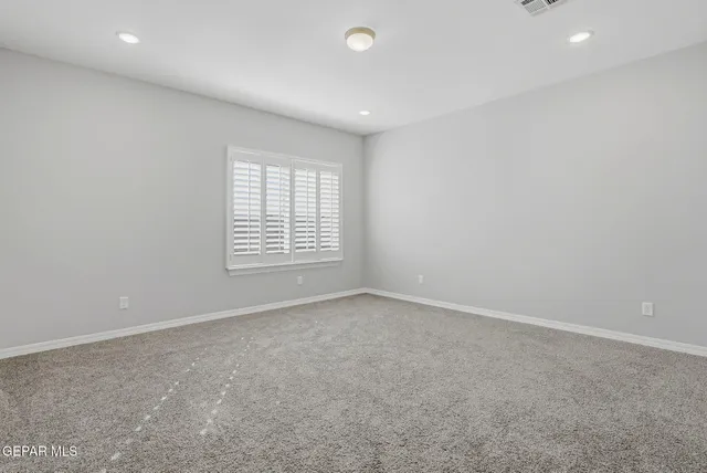 an empty room with windows and ceiling fan