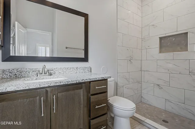 a bathroom with a granite countertop toilet sink and mirror