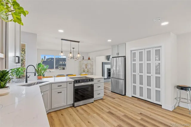 a kitchen with stainless steel appliances a stove a sink dishwasher a refrigerator white cabinets and wooden floor