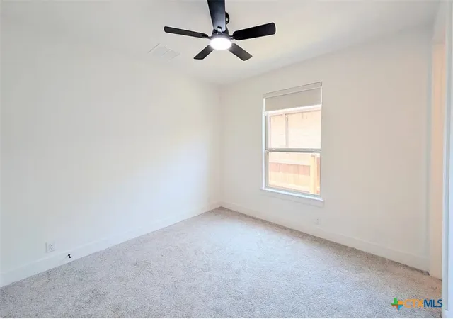 an empty room with a window and a fan