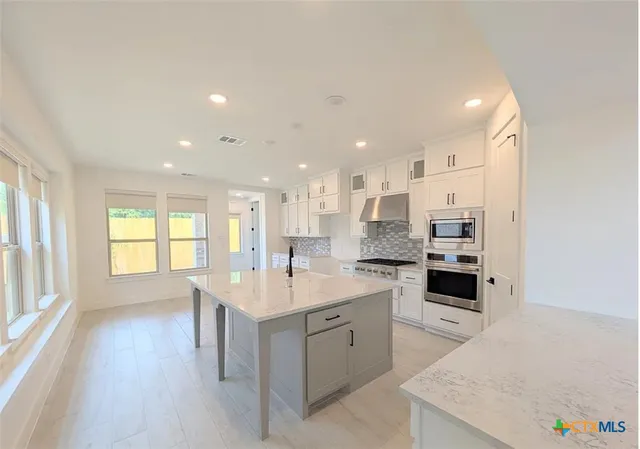 a large kitchen with a center island wooden floor and stainless steel appliances