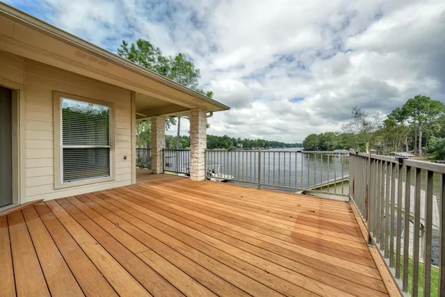 a view of a deck with wooden floor and fence next to a yard