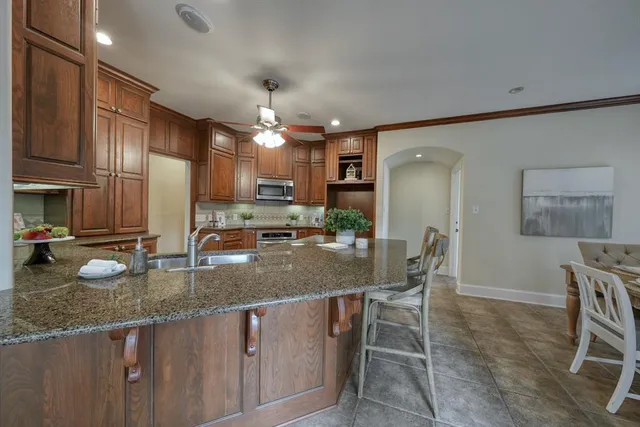 a kitchen with stainless steel appliances granite countertop a sink a stove a dining table and chairs