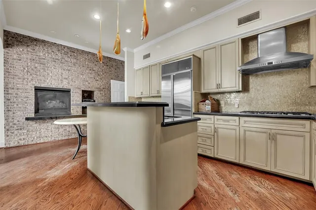 a kitchen with stainless steel appliances granite countertop a stove top oven a sink dishwasher and a microwave oven on the wooden floor