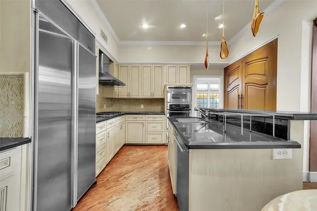 a kitchen with stainless steel appliances granite countertop a sink a stove and a refrigerator