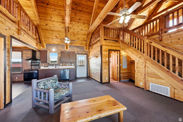 10937 South County Road, Unit 29 Duchesne, UT 84021 - Photo 5 of 41 Open-concept living space featuring vaulted wood ceilings, a prominent wood staircase leading to an upper loft, and wood-paneled walls throughout