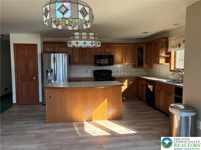 a large kitchen with stainless steel appliances granite countertop a stove top oven a sink dishwasher a dining table and chairs with wooden floor