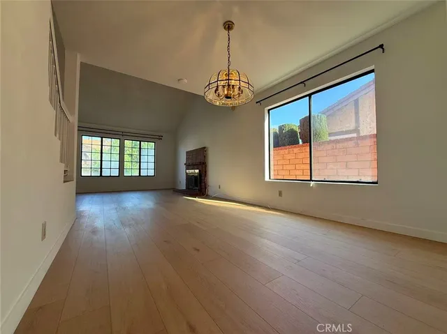 an empty room with wooden floor windows and glass door