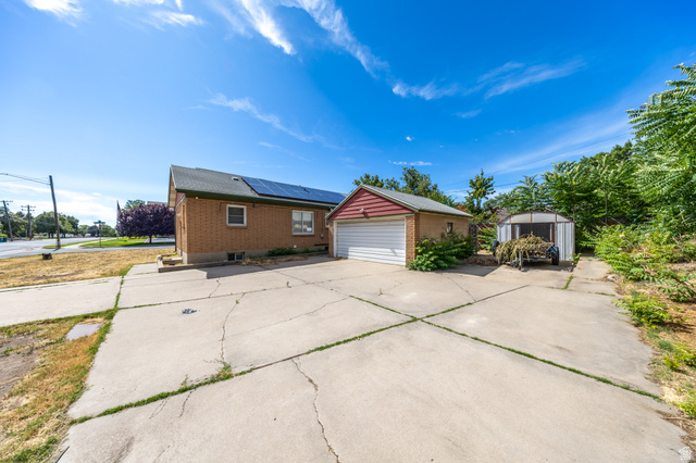 193 Locust Street Clearfield, UT 84015 - Photo 21 of 29 Expansive concrete driveway servicing a brick exterior residence, a detached garage with a red siding accent, and a separate storage structure