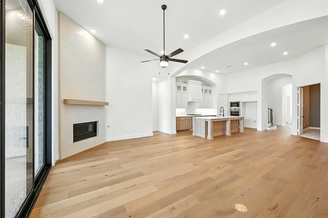 a view of an empty room with a fireplace and a chandelier fan