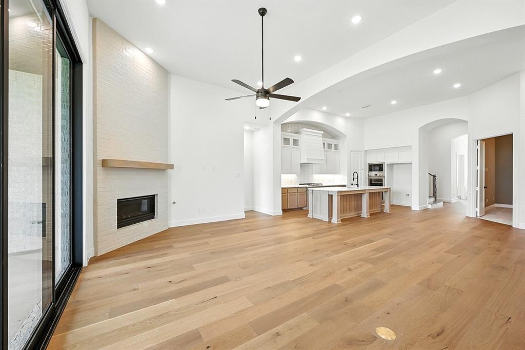 4013 Trellis Drive Prosper, TX 75078 - Photo 8 of 35 a view of an empty room with a fireplace and a chandelier fan