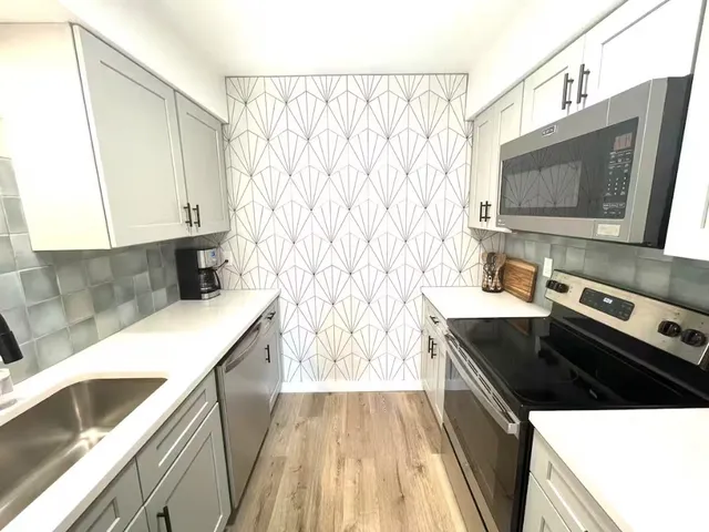 a kitchen with stainless steel appliances a stove a sink and a microwave