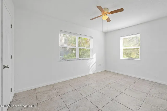 an empty room with windows and fan