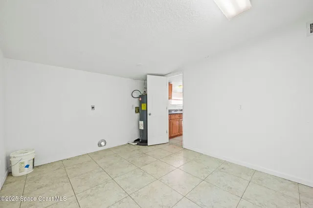 an empty room with chandelier fan and windows
