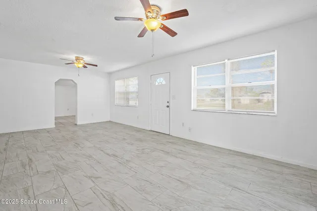 an empty room with fan and windows