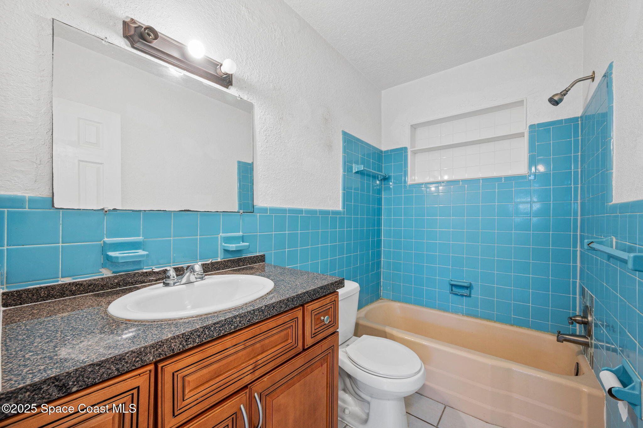 907 Espanola Way Melbourne, FL 32901 - Photo 8 of 31 a bathroom with a granite countertop sink a toilet a mirror a bathtub and shower