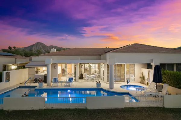 a view of a house with pool and chairs