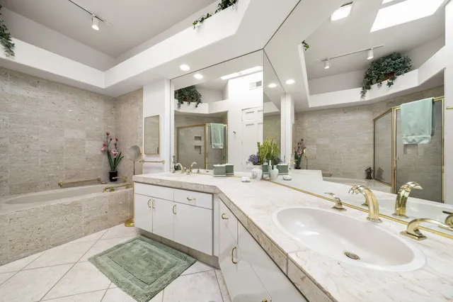 a bathroom with a sink double vanity granite tub shower and a mirror