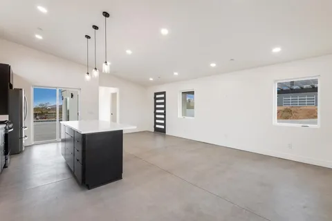 a large kitchen with stainless steel appliances kitchen island granite countertop a refrigerator a sink a stove and oven with wooden floor